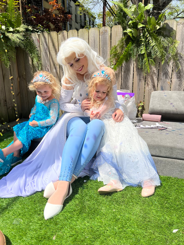 Elsa and two little princesses pose at an outdoor birthday party
