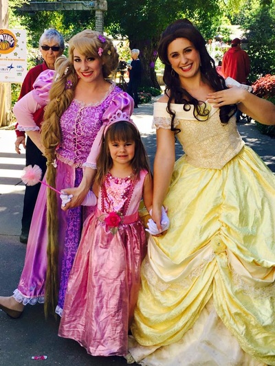 Belle and Rapunzel hold hands with a little princess in NYC