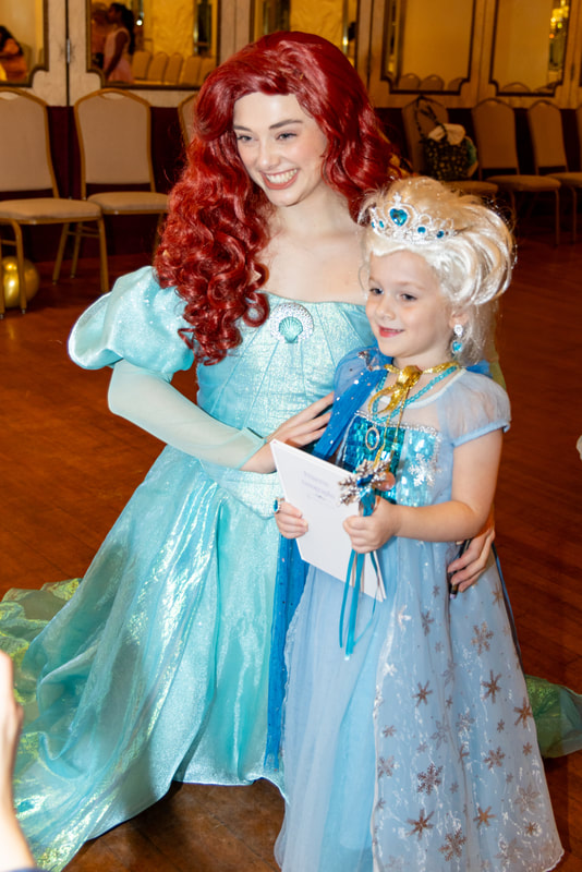 Ariel poses with a little girl dressed as Elsa at the princess ball